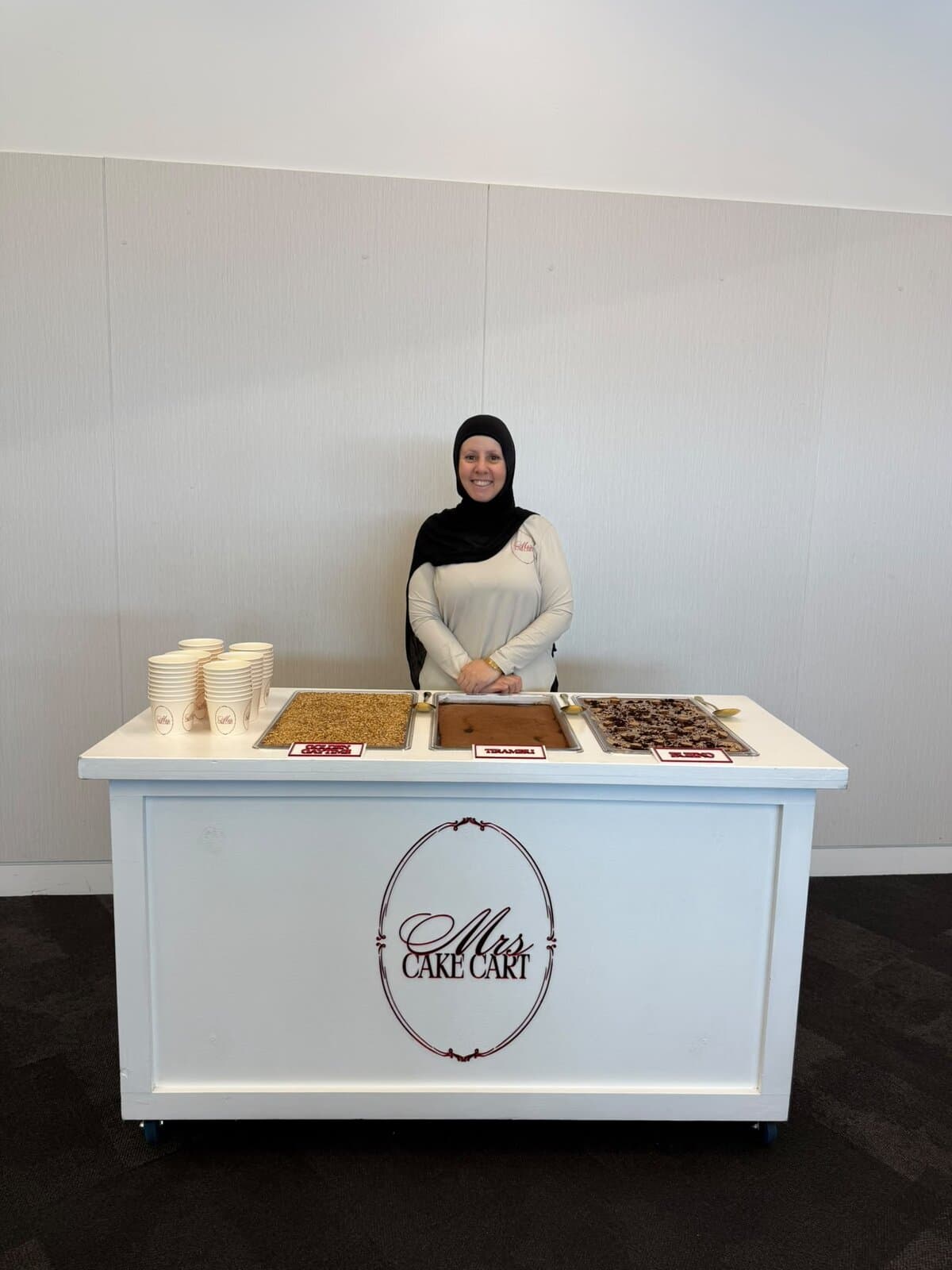 Sara behind her cart with three trays of dessert